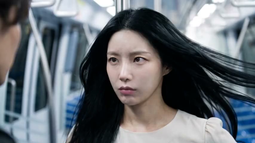 A woman turning to look back down a train carriage, hair still moving.